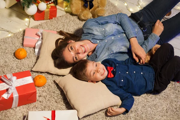 Mom and son on New Years Eve at Christmas tree gifts lights garlands — Stock Photo, Image