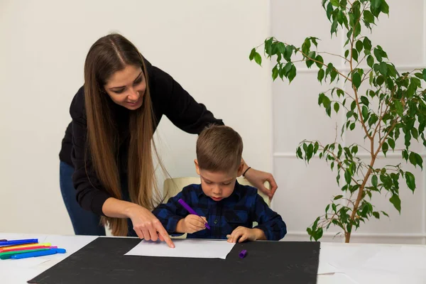 Mama i syn uczą się rysować w domu przy stole. — Zdjęcie stockowe