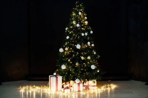 圣诞树，上面有礼物和灯光装饰着新年的黑色背景 — 图库照片