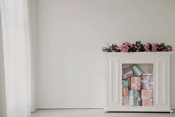 Chimenea blanca con flores y regalos en el interior de la habitación blanca — Foto de Stock