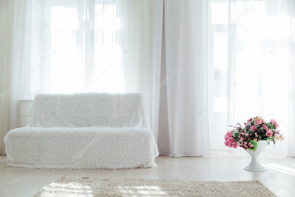 white sofa with flowers in the interior of the room with windows