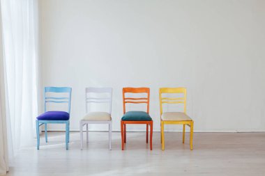 Boş beyaz bir odanın içinde çok renkli sandalyeler.