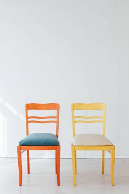 Boş beyaz bir odanın içinde çok renkli sandalyeler.