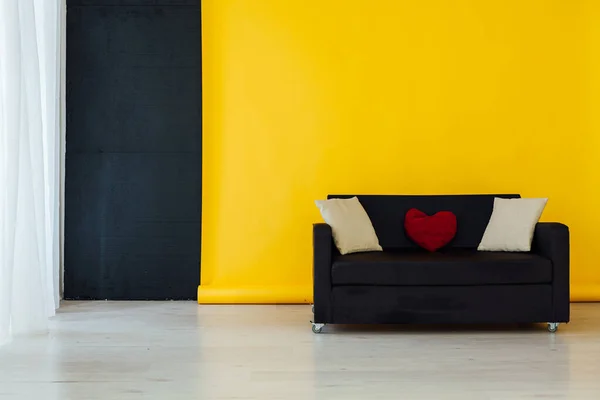Sofá preto no interior da sala com um fundo amarelo — Fotografia de Stock