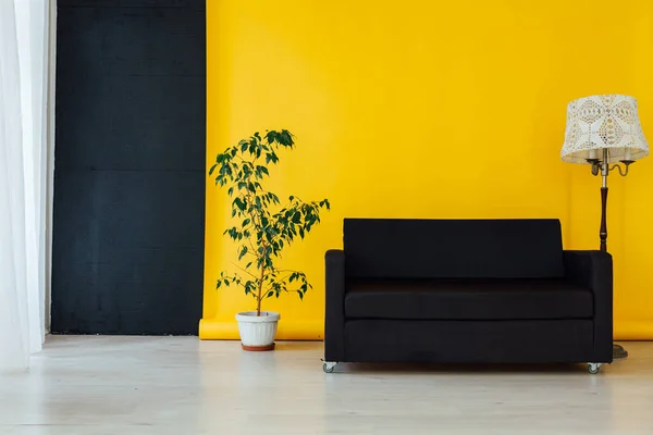 Sofá negro en el interior de la habitación con un fondo amarillo — Foto de Stock