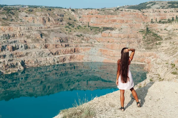Beautiful woman in dress looks at the view of a mountain lake — Stock Photo, Image