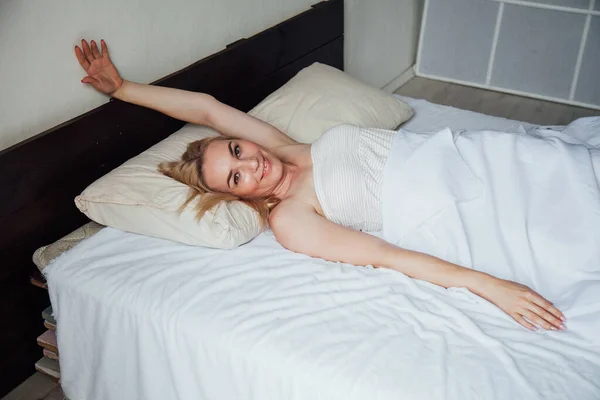 Hermosa mujer rubia se despertó por la mañana en el dormitorio en la cama —  Fotos de Stock