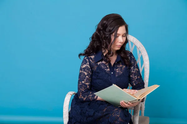 一个亚洲女人的画像读一本蓝色背景的书 — 图库照片