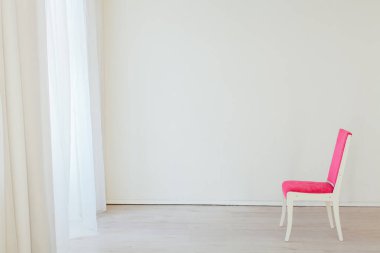 Boş beyaz bir odanın içinde pembe, eski bir sandalye.