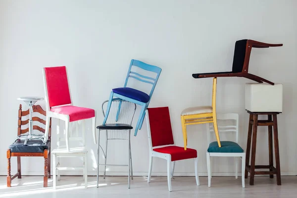 Vele veelkleurige stoelen in de rotzooi van de witte kamer — Stockfoto