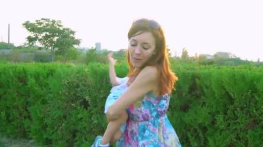 Anne gün batımında oğlunu kollarında döndürüyor.