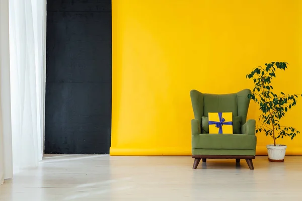 Zelené křeslo s dárkem v pokoji se žlutým pozadím — Stock fotografie
