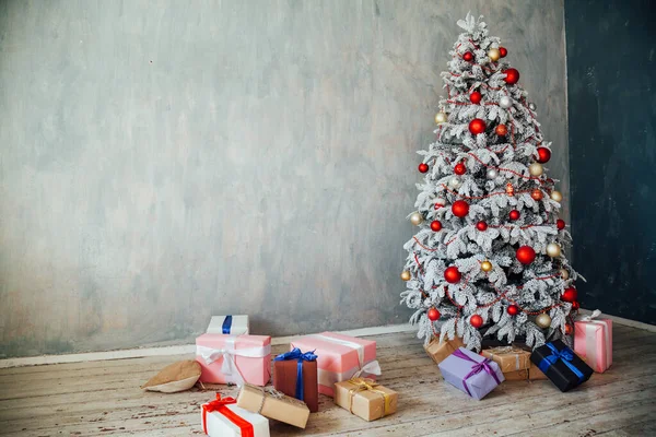 Рождественская снежная елка с подарками в белой комнате зимой — стоковое фото