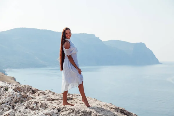 A beautiful woman with long hair in a dress looks at the landscape — Stock Photo, Image