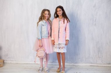 Gri bir arka planda beyaz pembe elbiseli iki güzel moda kızın portresi.
