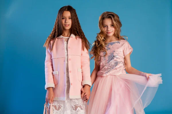 Ritratto di due belle ragazze alla moda in abiti rosa bianchi su sfondo blu — Foto Stock