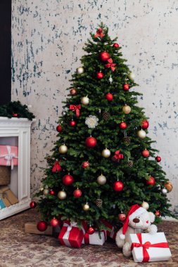 Yatak odasının içinde yeşil bir Noel ağacı yatağı ve yeni yıl dekorasyonu için kırmızı hediyeler var.