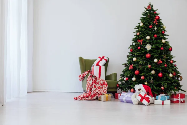 Beyaz odanın içi, yeni yıl için kırmızı hediyelerle dolu yeşil bir Noel ağacı.