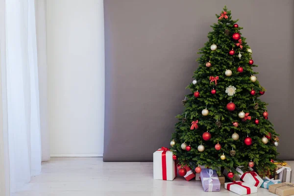 部屋のインテリアは 冬の休日の新年の装飾のための赤い贈り物と緑のクリスマスツリーです — ストック写真