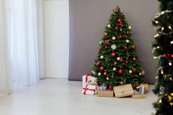 部屋のインテリアは 冬の休日の新年の装飾のための赤い贈り物と緑のクリスマスツリーです — ストック写真