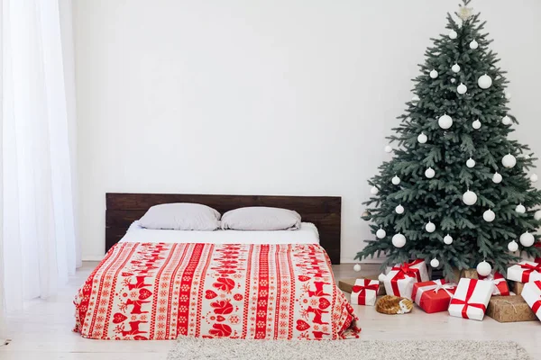 白色卧室的内部 有一张床 上面有一棵蓝色的圣诞树 上面有新年装饰用的红色礼物 — 图库照片