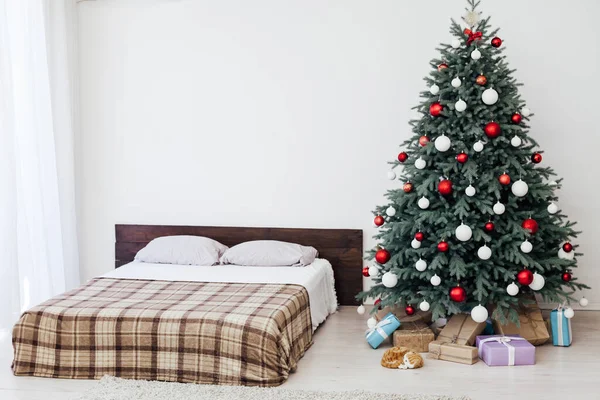 白色卧室的内部 有一张床 上面有一棵蓝色的圣诞树 上面有新年装饰用的红色礼物 — 图库照片