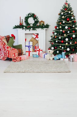 Parlak ışıklandırılmış noel ağacı ve pencerenin yanında bir sürü hediye.