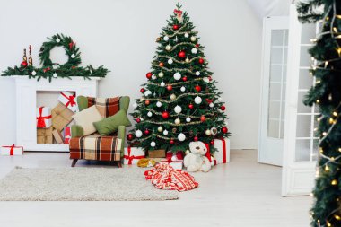 Parlak ışıklandırılmış noel ağacı ve pencerenin yanında bir sürü hediye.