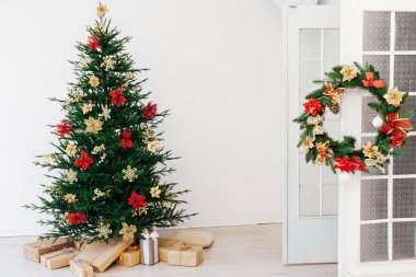 Zarif bir koltuğu olan şık bir Noel İskandinav iç mimarisi. Huzur evi. Hediyeler ve hediyeler Noel ağacının altında güneşli oturma odasında ışık ve mücevherlerle