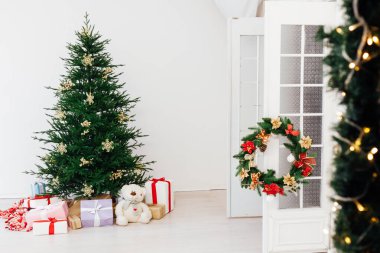 Zarif bir koltuğu olan şık bir Noel İskandinav iç mimarisi. Huzur evi. Hediyeler ve hediyeler Noel ağacının altında güneşli oturma odasında ışık ve mücevherlerle