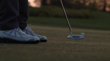 Golf oyuncu bir topu delikten koyuyor