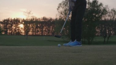 Junior golf oyuncu bir topu delikten koyuyor