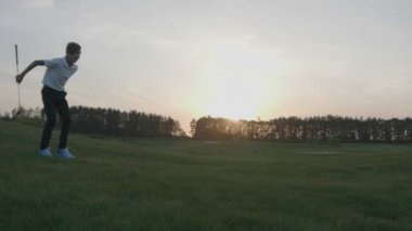 Mutlu çocuk golfçü. Gün batımında golf sahasında neşeli genç çocuk