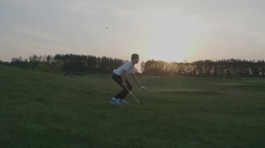 Mutlu çocuk golfçü. Gün batımında golf sahasında neşeli genç çocuk
