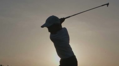 Gün batımında golf çantası ile çocuk golfçü silüeti