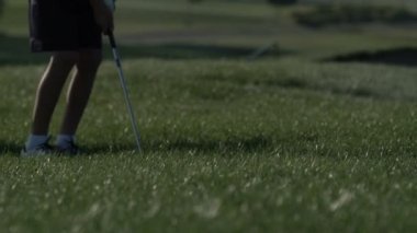 Junior golfçü yaz yeşil çim üzerinde atış isabet ile golf oynamak