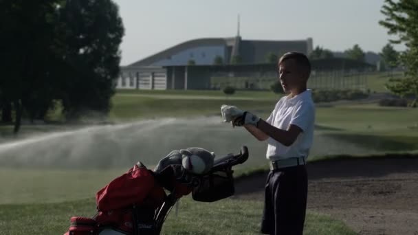 Junior golfista jugando al golf en verano con tiro de golpear en la hierba verde — Vídeos de Stock