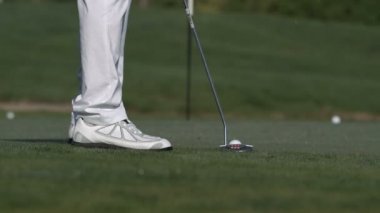 erkek golfçü bir golf topu deliğe koyarak