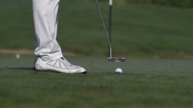 erkek golfçü bir golf topu deliğe koyarak