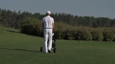 Çanta taşıyor ve golf sahasında sonraki delik için yürüyen adam golfçü
