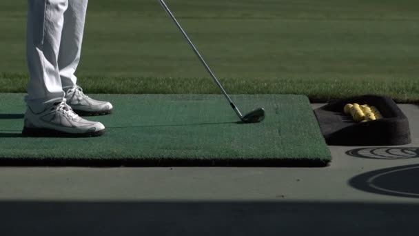 若いゴルファーの練習時の航続距離、サイドからの眺め彼のゴルフ スイング — ストック動画