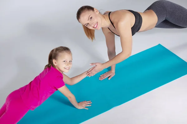 Mujer entrenador y 10 años de edad chica están haciendo ejercicios de gimnasio — Foto de Stock