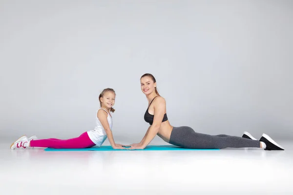 Hermosa mujer y su hija están haciendo ejercicios en esteras — Foto de Stock