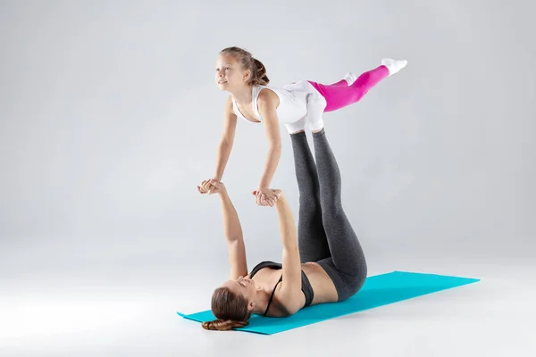 Hermosa mujer y su hija están haciendo ejercicios en esteras — Foto de Stock