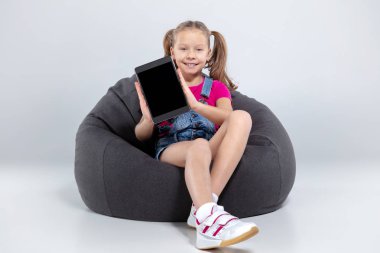 Smartphone kullanarak ve kulaklık ile müzik dinlemek mutlu küçük kız öğrenci
