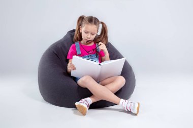 Genç kız bardaklarda bir gri fasulye çanta üzerine bir kitap okuma