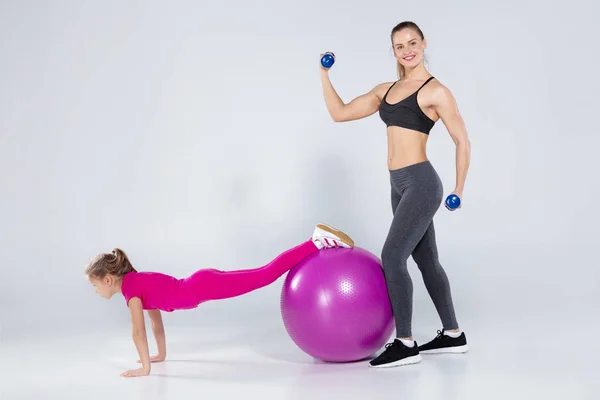 Athletic woman and nice girl doing sport exercises — Stock Photo, Image