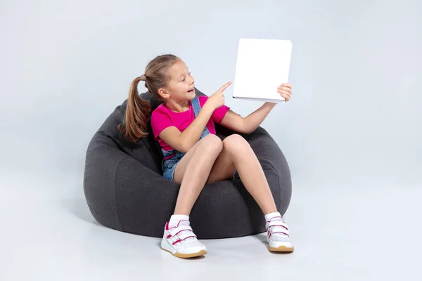 Joven chica bonita de la escuela sosteniendo libro blanco — Foto de Stock