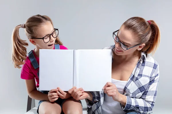 Mosolygó gyönyörű nő, és a lánya, szemüveg, könyv — Stock Fotó