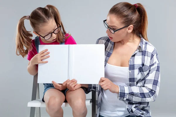 Krásná žena a její dcera v brýlích s knihou — Stock fotografie